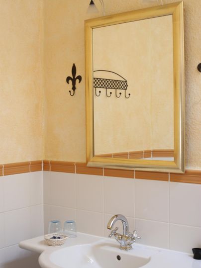 Ein Badezimmer mit einem Waschbecken und einem großen Spiegel. Die Wände sind in sanften Farben gestrichen und es gibt zwei Gläser auf dem Waschbecken.