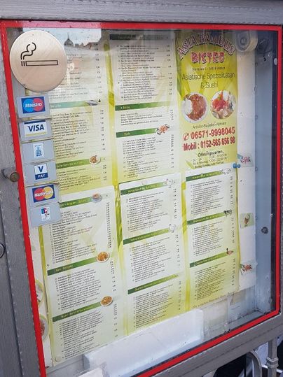 Ein Menü in einem Schaufenster, das verschiedene Speisen anbietet. Telefonnummern und Zahlungsmethoden sind ebenfalls angegeben.