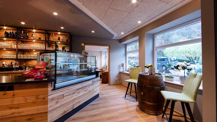 Eine gemütliche Innenausstattung mit einer Holzbar und zwei Sitzgelegenheiten. Große Fenster bieten einen Blick nach draußen und sorgen für viel natürliches Licht.