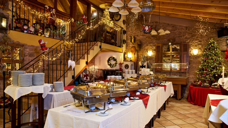 Ein festlich dekoriertes Restaurant mit Buffets und einem Weihnachtsbaum. Die Atmosphäre ist gemütlich und einladend.