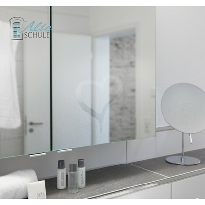 Ein modernes Badezimmer mit einem beschlagenen Spiegel, auf dem ein Herz zu sehen ist. Auf der Ablage befinden sich einige Pflegeprodukte und ein Handtuch.