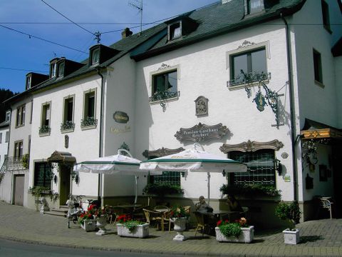 Een charmant pension met een uitnodigend terras. Kleurrijke bloemen en parasols creëren een gezellige sfeer.