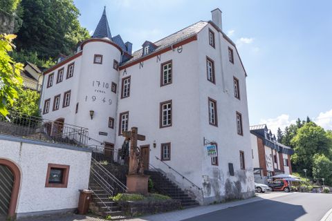 Historisches Gebäude in Gerolstein mit der Aufschrift 'Anno 1710' und '1949', Treppen und Statue im Vordergrund, blauer Himmel im Hintergrund.