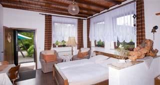 Ein gemütliches Schlafzimmer mit zwei Betten und Holzdecken. Große Fenster lassen viel Licht herein und bieten einen Blick auf den Garten.