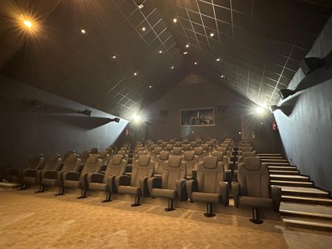 A modern cinema with comfortable seats and dimmable lighting. The room appears inviting and cozy for film screenings.