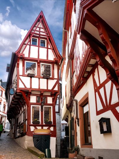 Ein historisches Fachwerkhaus mit roten und weißen Elementen in einer charmanten Straße. Die Architektur spiegelt den traditionellen Stil der Region wider.
