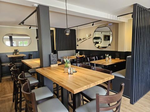 Een modern restaurant met houten tafels en stoelen. De muren zijn in neutrale kleuren gehouden en weerspiegelen een uitnodigende sfeer.