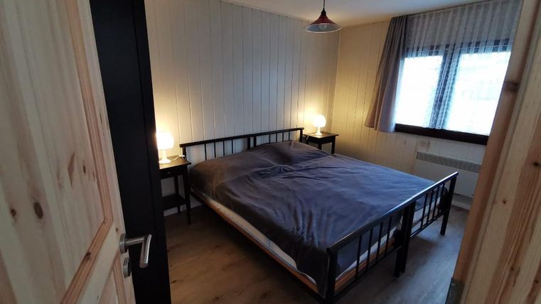Een gezellige slaapkamer met een groot bed en twee nachtkasten. Het licht is warm en creëert een uitnodigende sfeer.