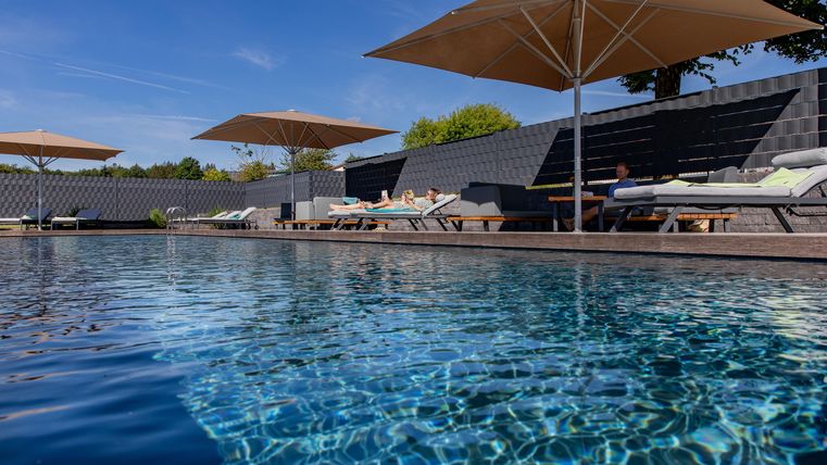 Een mooie zwembad met ligbedden en parasols. De lucht is helder en blauw, ideaal om te ontspannen.