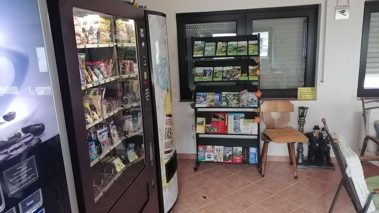 Ein kleiner Raum mit einem Snackautomat und einem Bücherregal. Es gibt auch ein paar Stühle zum Sitzen.