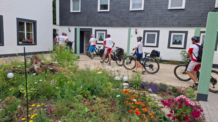 A group of cyclists is riding into a courtyard.