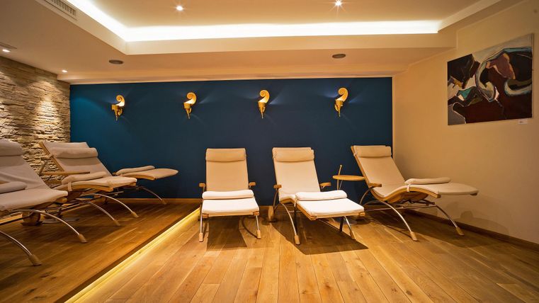 A relaxing wellness area with modern loungers and a warm wooden floor. The walls are painted in calming colors, with artistic accents.