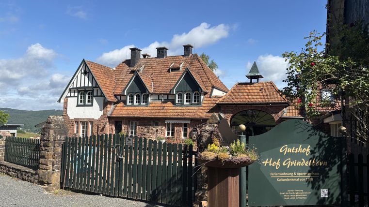 Een charmante guesthouse met traditionele architectuur en een uitnodigende entree. De tuin is mooi aangelegd en het weer is helder.