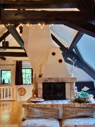 A cozy living room with wooden structures and a fireplace. The atmosphere is warm and inviting, perfect for relaxing.