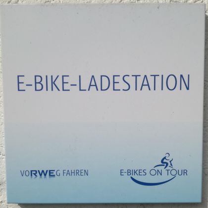 E-Bike-Ladestation mit Hinweis auf das Anbieterlogo. Ideal für E-Bike-Fahrer zur Stromauffüllung.