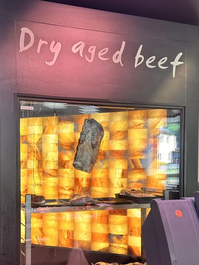 A shelf with dry-aged beef. In the background, a warm-colored wall highlights the meat.