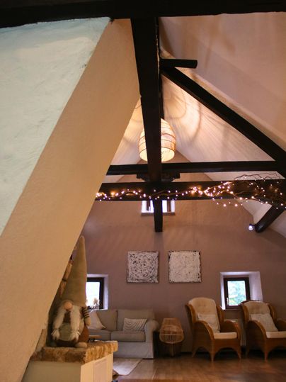 A cozy room with slanted walls and wooden beams. Inviting furniture and soft lighting create a warm atmosphere.