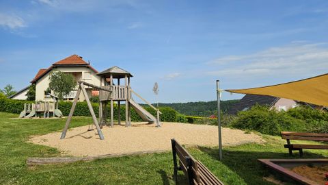 Sand playground with wooden children's play towers and a large sandbox with a sun sail.