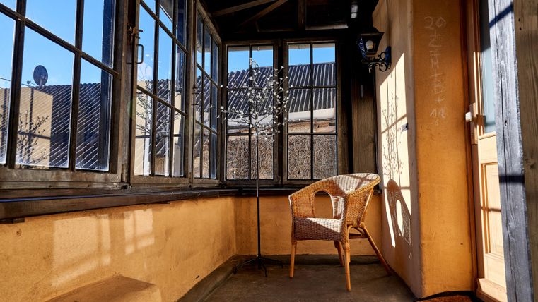 A cozy winter garden with large windows and a rattan chair. The light gently falls on the walls, creating an inviting atmosphere.