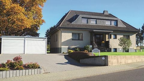 Een modern eengezinswoning met een verzorgde voortuin. Links bevindt zich een garage en op de achtergrond straalt de herfstboom.