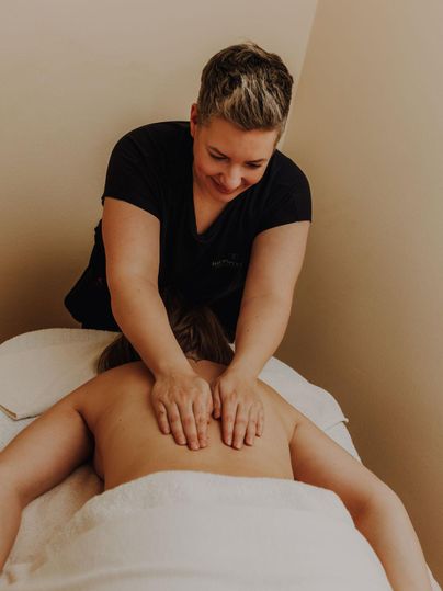 Eine Relaxmassage wird von einer Fachkraft durchgeführt. Die Person auf der Liege entspannt sich unter den Händen der Masseurin.