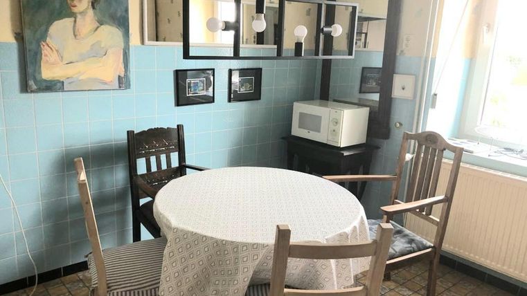 Ein gemütlicher Essbereich mit einem runden Tisch und vier Stühlen. Die Wände sind blau gestrichen und ein Gemälde ist sichtbar.