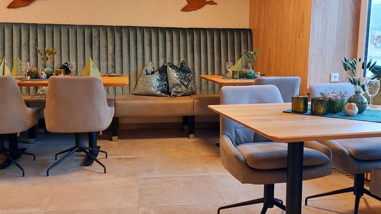 Ein modern gestalteter Restaurantbereich mit gemütlichen Stühlen und Tischen. Die Wände sind mit eleganten dekorativen Elementen geschmückt.