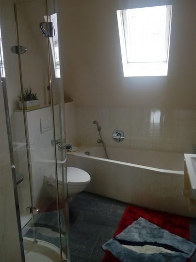 A modern bathroom with a shower and a bathtub. It has bright walls and a gray floor with a carpet.