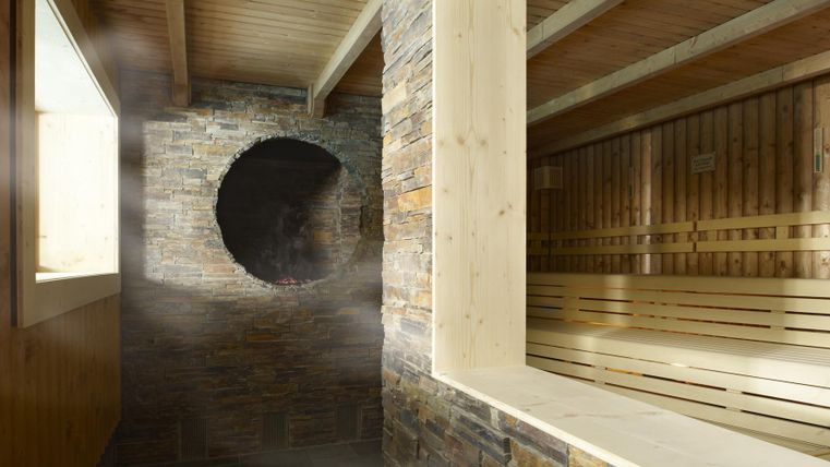 Een lichte sauna-ruimte met houten en stenen materialen. Stoom is aanwezig, en grote ramen zorgen voor natuurlijk licht.