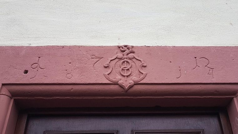 Ein historisches Türgestell mit einer Schnitzerei darüber. Die Jahreszahl und dekorative Elemente sind sichtbar.