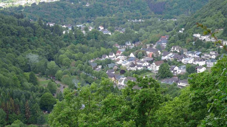 Eine malerische Aussicht auf ein kleines Dorf, umgeben von grünen Wäldern. Die Häuser sind sanft in die Landschaft eingebettet.