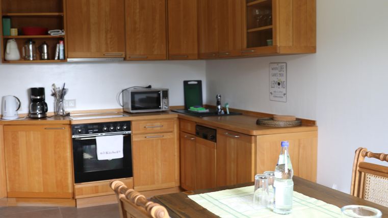 A cozy kitchen with wooden cabinets and modern appliances. The dining table is set and ready for a meal.