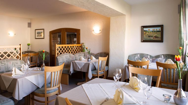 Ein gemütliches Restaurant mit Tischdecken und Blumenarrangements. Die Einrichtung ist hell und einladend.