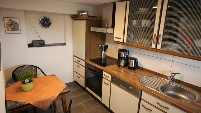 Een kleine, moderne keuken met houten planken en een gezellige eethoek. Ze is goed verlicht en goed uitgerust.