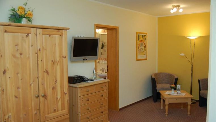 Ein gemütliches Zimmer mit Holzschränken und einem kleinen Sitzecke. Der Raum ist hell und freundlich gestaltet.