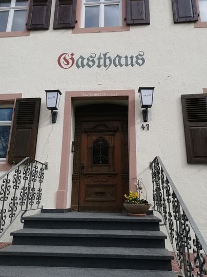 Ein einladendes Gasthaus mit einer schönen Eingangstür. Die Stufen sind von einem dekorativen Geländer umgeben.