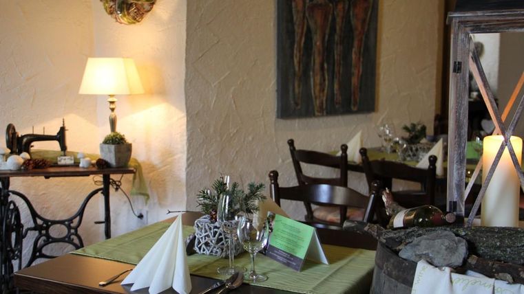 Een gezellig restaurant met stijlvol gedecoreerde tafels. Achterin hangen kunstwerken en een mooie lamp.