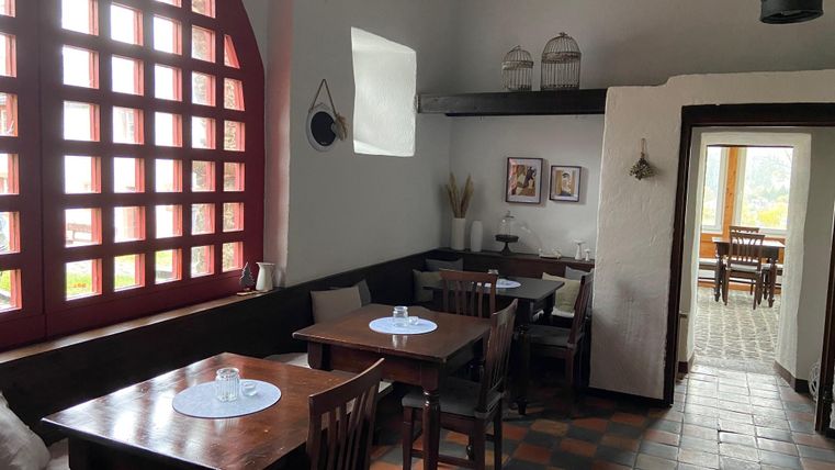 Ein gemütliches Restaurant mit Holztischen und einer großen Fensterfront. Die Atmosphäre ist hell und einladend, mit dekorativen Elementen an den Wänden.