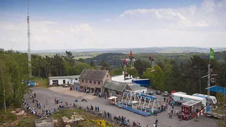 A recreational area with rides and a historic building. In the background, trees and a wide landscape are visible.