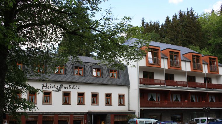 Een charmant hotelgebouw met twee verschillende architectuurstijlen. Het gebouw is omringd door bomen, wat een rustige sfeer creëert.