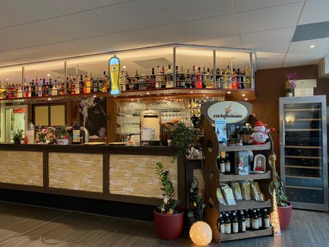 Interior view of the restaurant with a bar, shelves full of bottles, and decorations.
