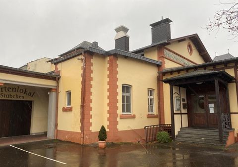 Een twee verdiepingen tellend gebouw met een gele gevel en rode accenten is te zien. Het heeft een traditioneel ontwerp en bevindt zich in een regenachtige omgeving.