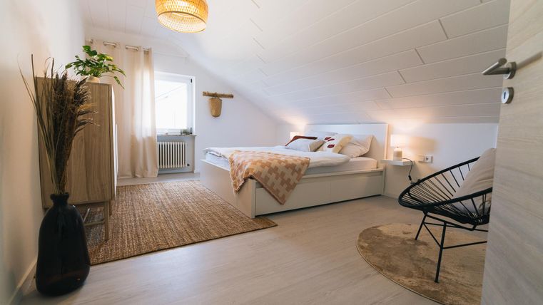 Een sfeervolle slaapkamer met een tweepersoonsbed, een grote raamwand en een stijlvolle inrichting. De ruimte is licht en vriendelijk, met een moderne decoratie en veel ruimte.