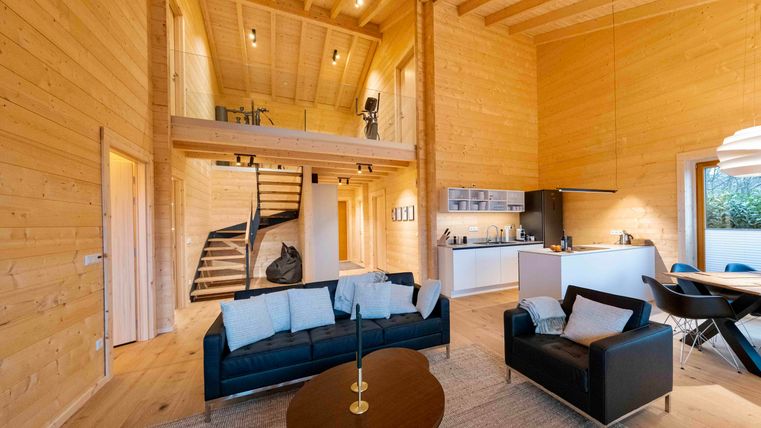 Eine moderne und helle Wohnung mit Holzvertäfelung und großen Fenstern. Der offene Wohnbereich verbindet Wohn- und Esszimmer mit einer modernen Küche.