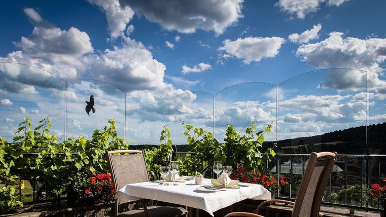 Een gezellige tafel op een terras met uitzicht op de natuur. De lucht is helder en versierd met mooie wolken.