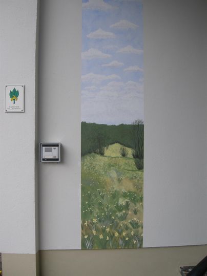A mural with a hilly landscape, green meadows, and blue sky. The lower area features yellow flowers in full bloom.