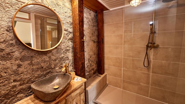 A modern bathroom with an elegant stone vanity and a spacious shower. The combination of wood and stone gives the room a warm atmosphere.
