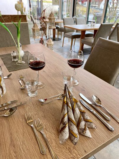 Ein eleganter Tisch in einem Restaurant, gedeckt mit Weingläsern und schön gefalteten Servietten. Die Atmosphäre ist einladend und gemütlich.