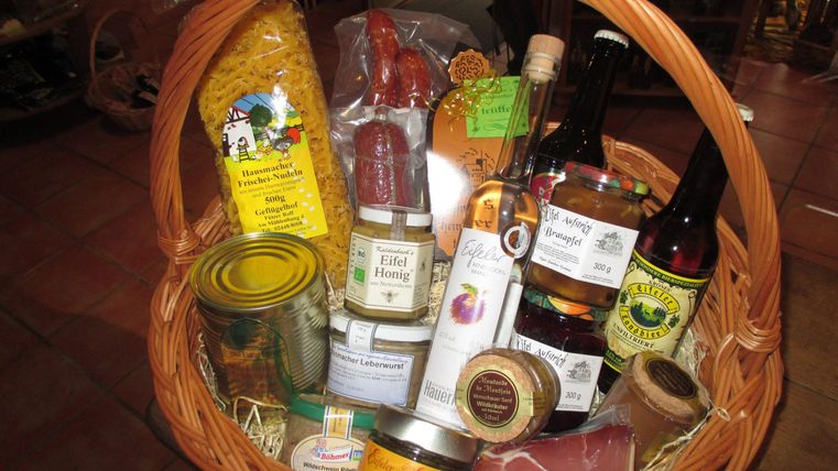 Een mand vol regionale levensmiddelen, waaronder pasta, honing, jam en dranken. De producten zijn zorgvuldig gerangschikt en stralen een rustieke, uitnodigende sfeer uit.
