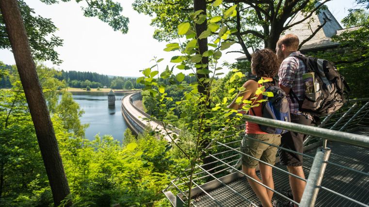 Twee wandelaars op een platform met uitzicht op de Dreilägerbachdam.